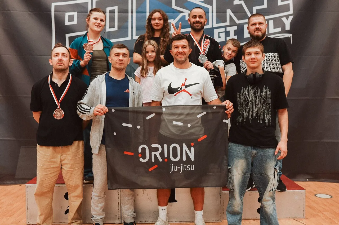 Drużyna Orion BJJ Wrocław z banerem klubu na podium